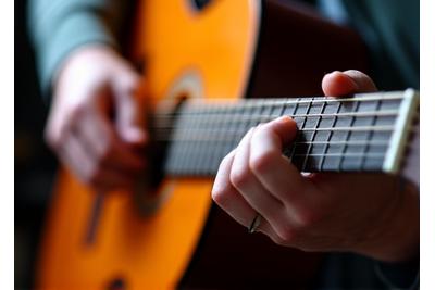 A person's hands expertly fretting an acoustic guitar.